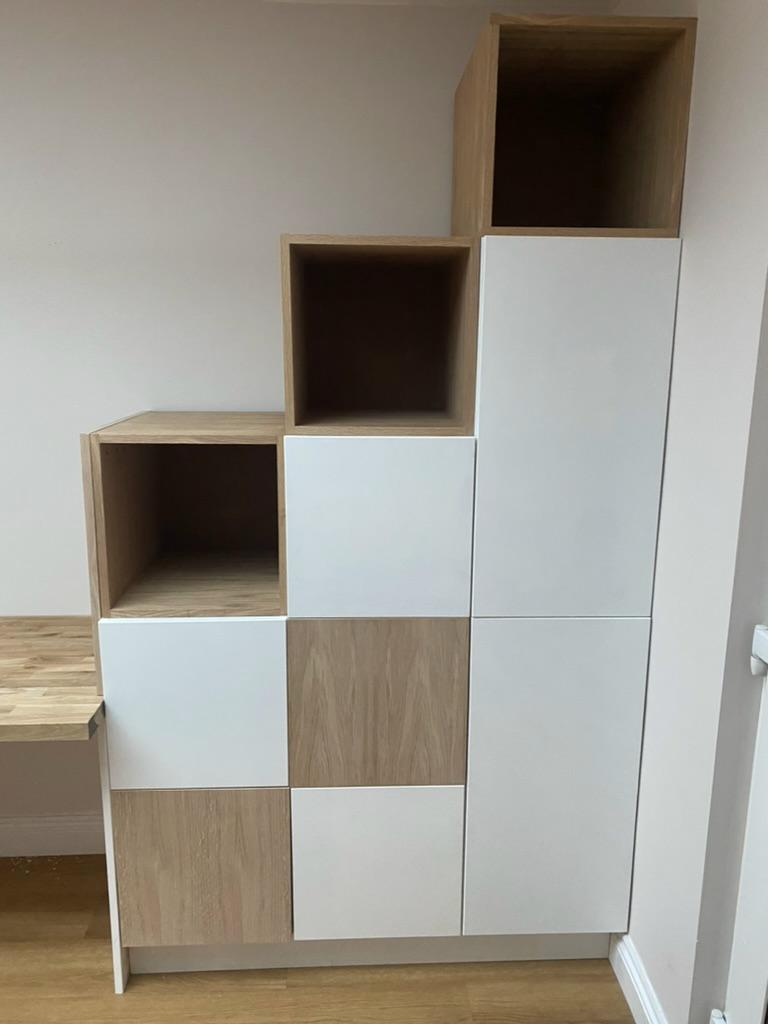 Bespoke staircase-shaped storage unit with alternating white gloss and oak veneer doors and open display cubbies, Cambridge