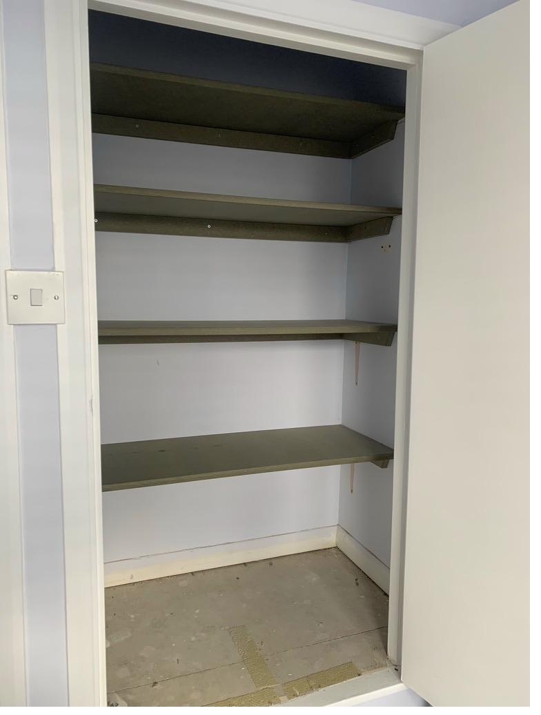Fitted alcove shelving unit with four dark green painted shelves and white painted surround, Cambridge