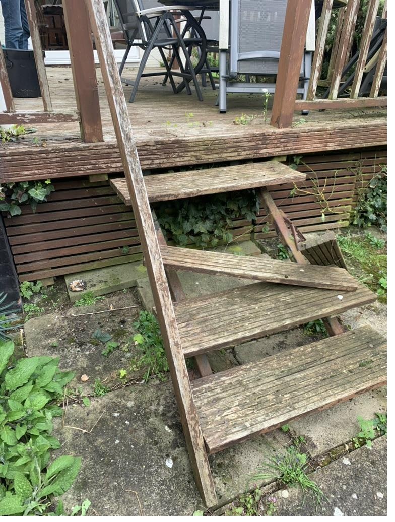 Weathered and rotten wooden deck staircase before replacement — showing structural deterioration and safety issues